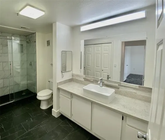 a bathroom with a granite countertop toilet a sink and a mirror