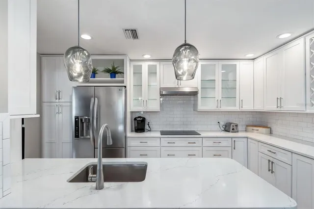 a kitchen with stainless steel appliances granite countertop a sink refrigerator and cabinets