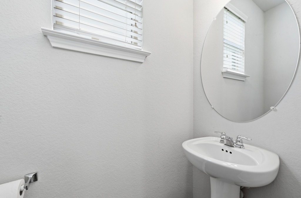 209 Noddy Road Buda, TX 78610 - Photo 14 of 27 Crisp walls frame a classic pedestal sink and an elegant oval mirror.