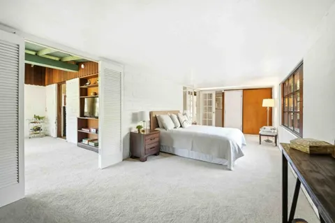 a spacious bedroom with a bed and glass door