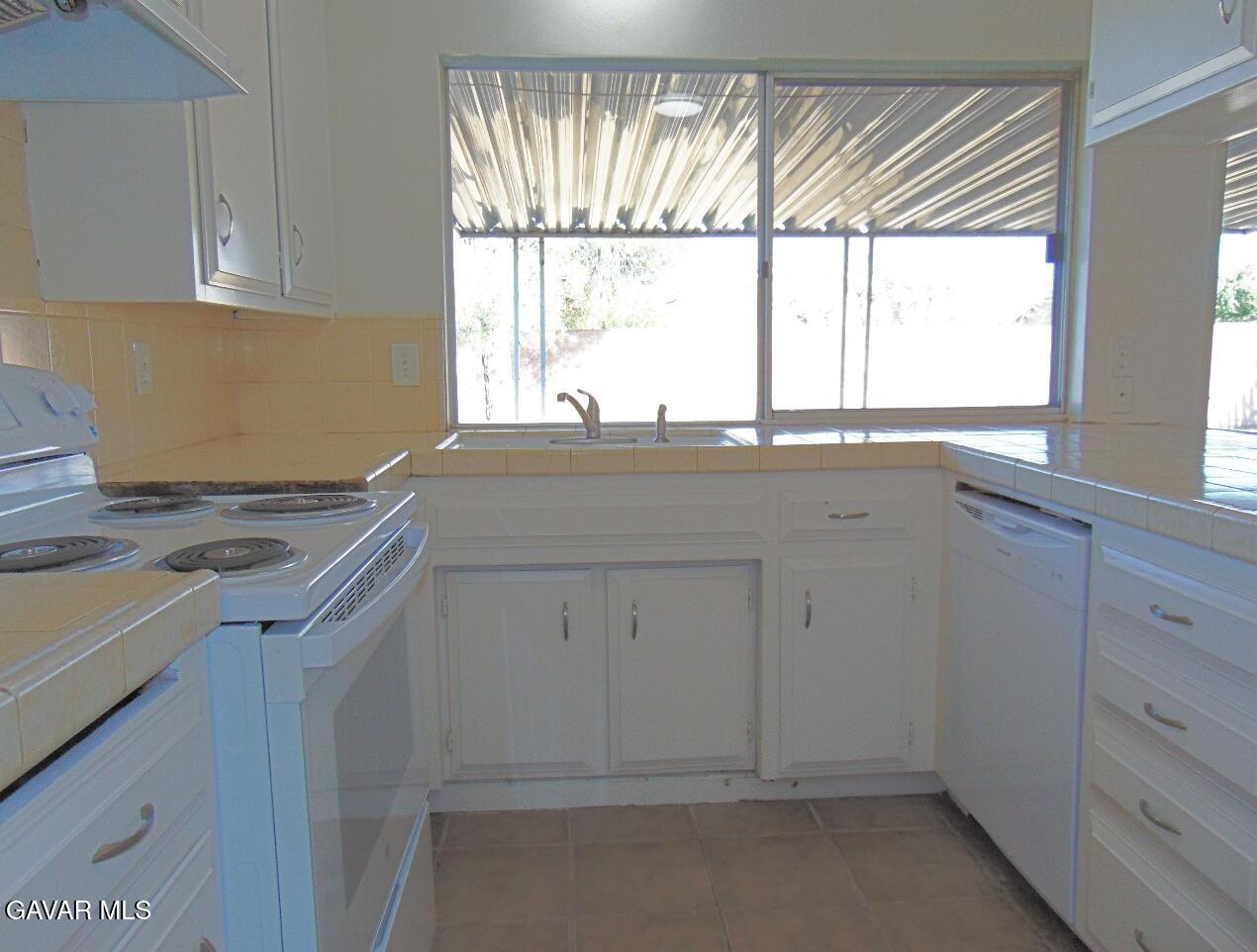1260 North El Prado Street Ridgecrest, CA 93555 - Photo 11 of 28 a kitchen with granite countertop white cabinets and a window