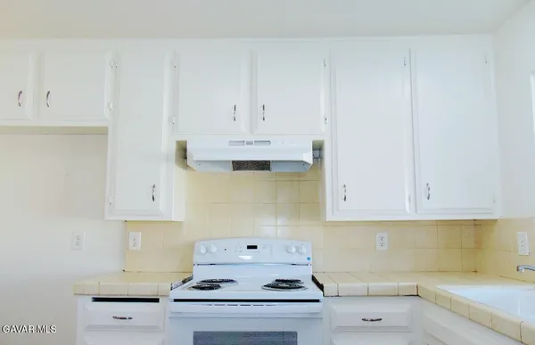 a kitchen with white cabinets and a stove with white countertops
