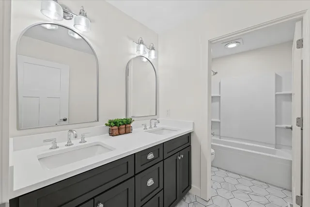 a bathroom with a double vanity sink mirror and bathtub