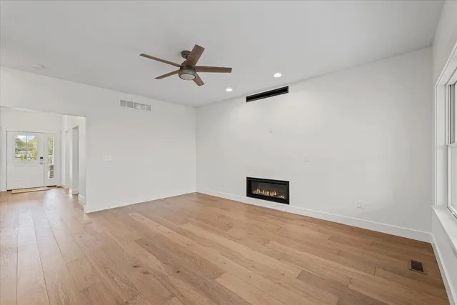 an empty room with wooden floor and windows