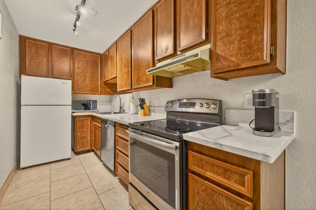 a kitchen with stainless steel appliances granite countertop a refrigerator a stove and a sink