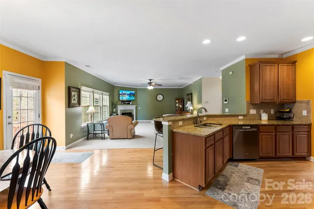 a kitchen with stainless steel appliances granite countertop a refrigerator a stove and a sink with wooden floor