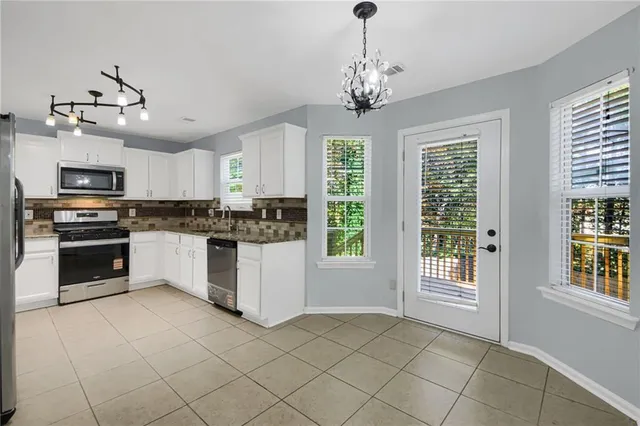 a kitchen with granite countertop stainless steel appliances cabinets and a window