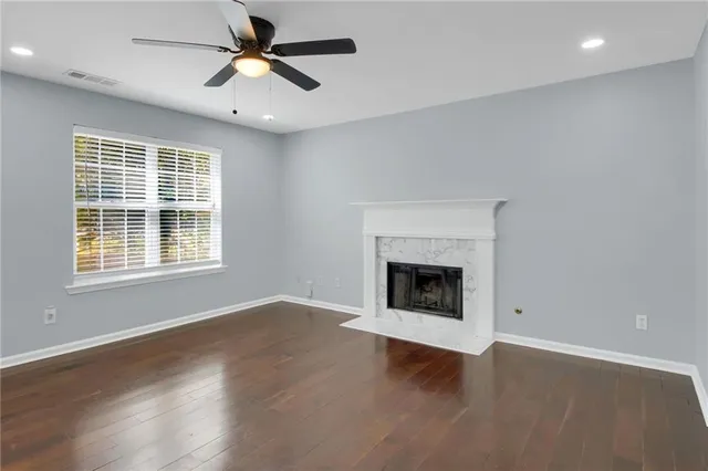 a view of an empty room with wooden floor fireplace and a window
