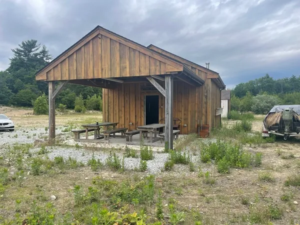 a backyard of a house with table and chairs under an umbrella