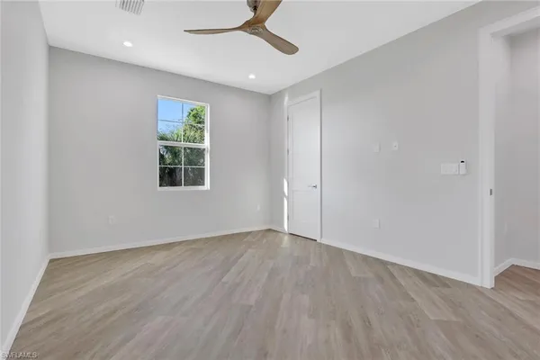 an empty room with wooden floor cabinet and windows