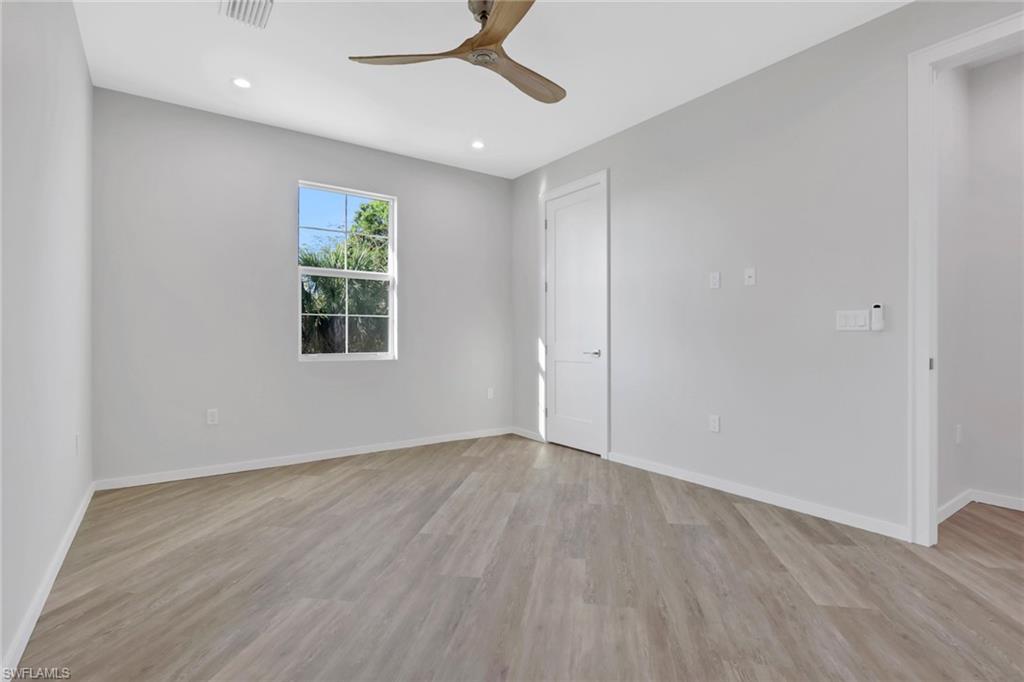 3500 Croton Road, Unit 102 Naples, FL 34104 - Photo 11 of 27 an empty room with wooden floor cabinet and windows