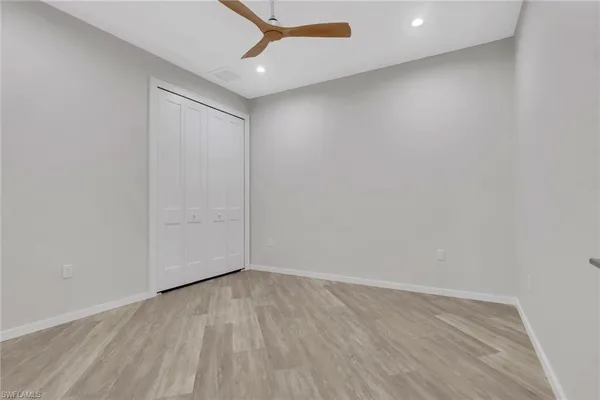 an empty room with wooden floor and ceiling fan