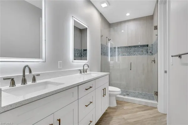 a bathroom with a double vanity sink toilet mirror and shower