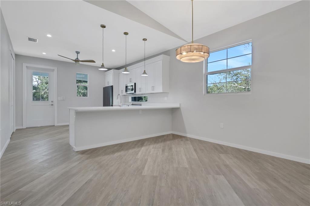 3500 Croton Road, Unit 102 Naples, FL 34104 - Photo 5 of 27 a large kitchen with granite countertop a stove a sink a window and a wooden floor