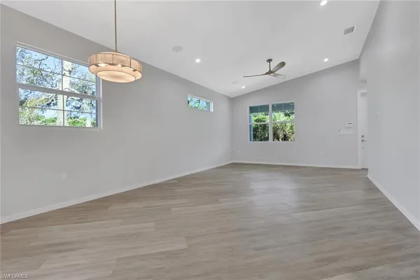 an empty room with windows and chandelier fan