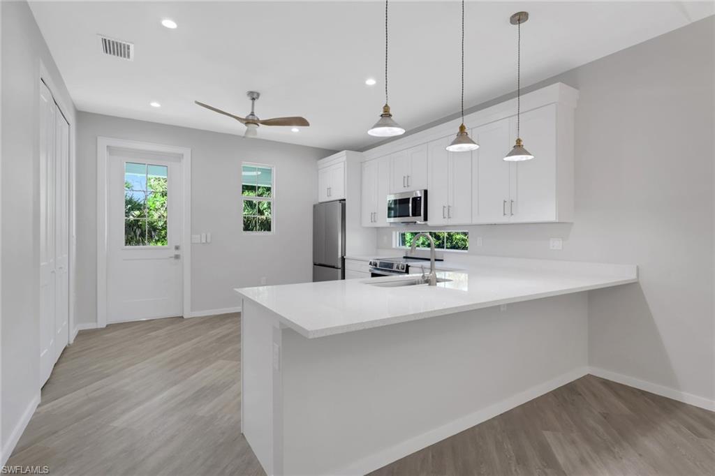 3500 Croton Road, Unit 102 Naples, FL 34104 - Photo 7 of 27 a kitchen with kitchen island a sink and a stove top oven