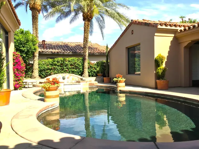 a swimming pool with outdoor seating and a garden