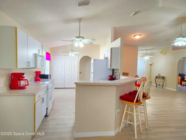 a kitchen view with stainless steel appliances kitchen island granite countertop a dining table chairs and a sink