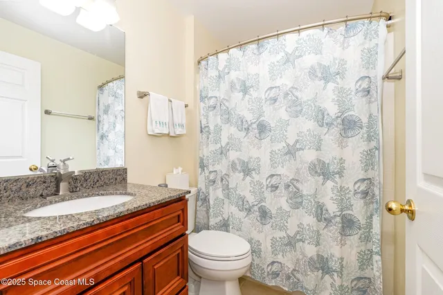 a bathroom with a granite countertop sink a toilet and a mirror