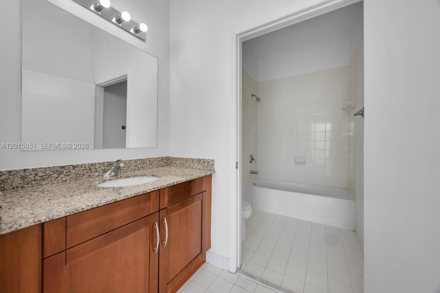 7275 Southwest 90th Street, Unit C719 Miami, FL 33156 - Photo 17 of 25 a bathroom with a granite countertop sink and a mirror