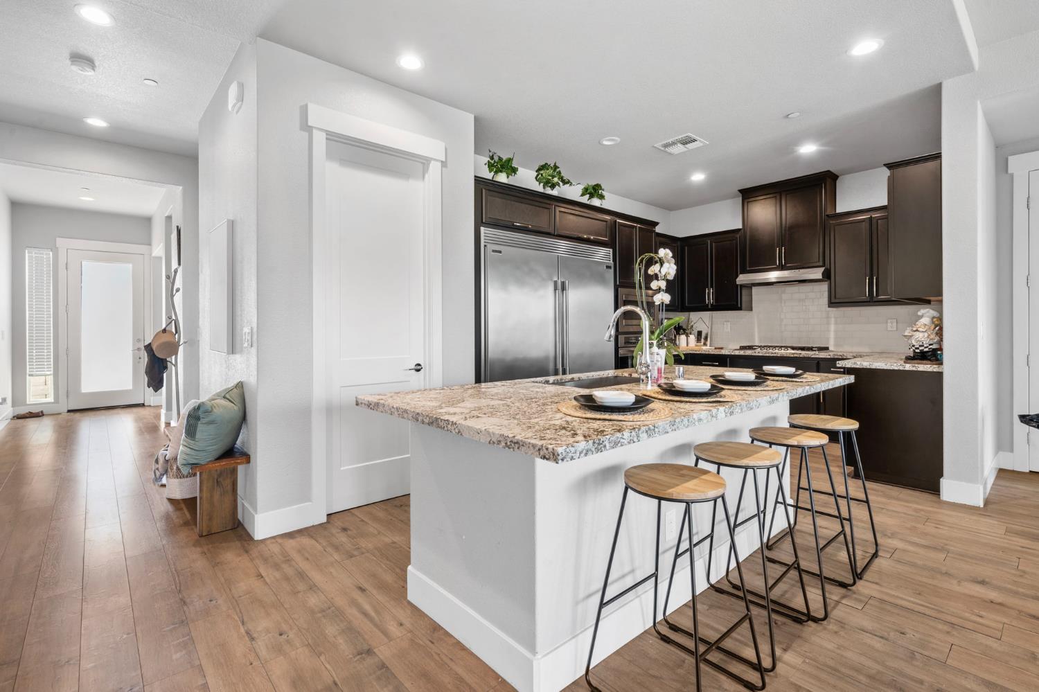 1847 Outrigger Lane Lathrop, CA 95330 - Photo 16 of 54 a kitchen with stainless steel appliances granite countertop a stove top oven a refrigerator and a dining table with wooden floor