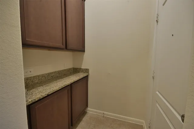a utility room with granite countertop cabinets and sink