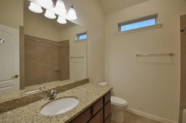 a bathroom with a granite countertop sink a toilet and a mirror