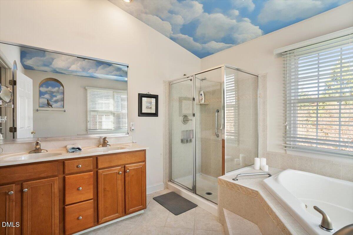 9120 Sanctuary Court Raleigh, NC 27617 - Photo 38 of 80 a spacious bathroom with a double vanity sink a mirror a bathtub and next to a window