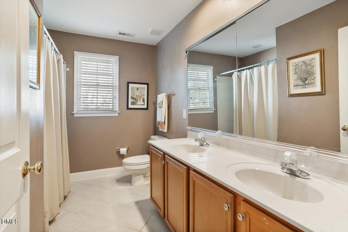 9120 Sanctuary Court Raleigh, NC 27617 - Photo 43 of 80 a bathroom with a double vanity sink toilet and a mirror
