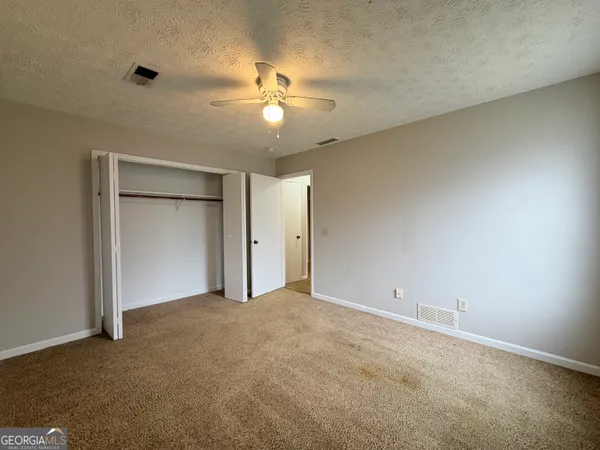 an empty room with closet and a chandelier fan
