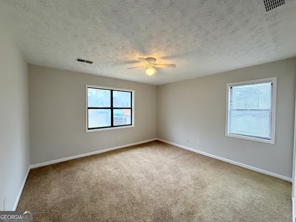 an empty room with a window and a fan