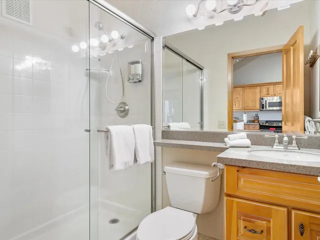 a bathroom with a granite countertop sink toilet a mirror and shower