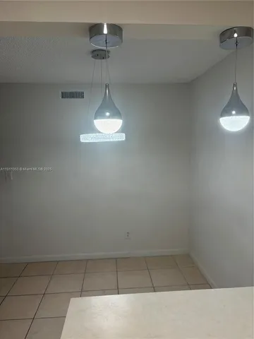 a view of an empty room with a chandelier fan