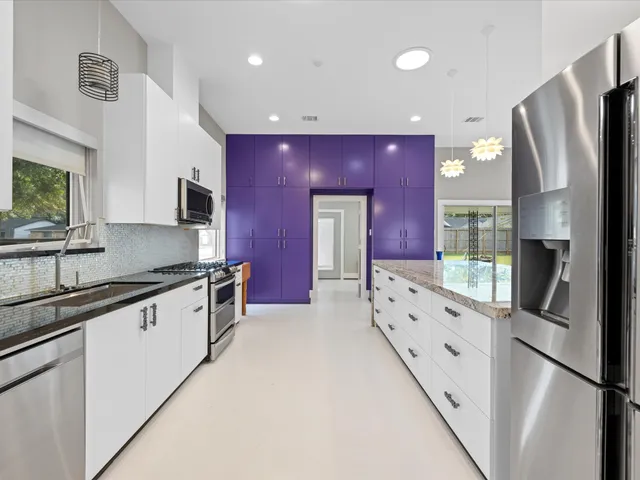 a kitchen with granite countertop a refrigerator a sink a stove top oven