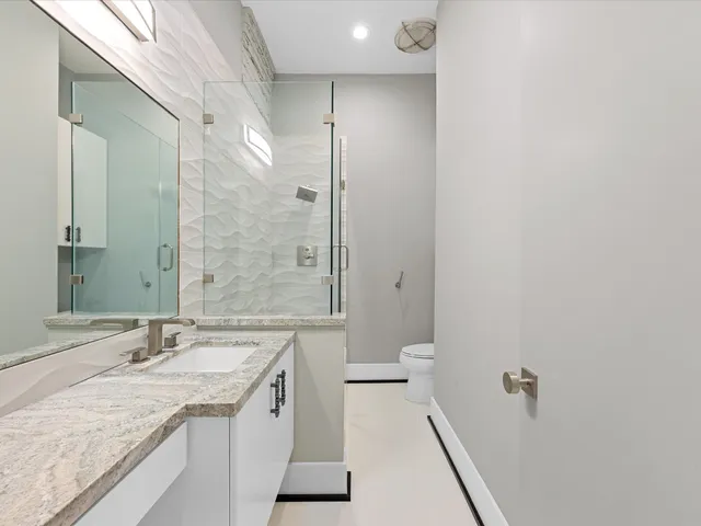a bathroom with a granite countertop sink a toilet and shower