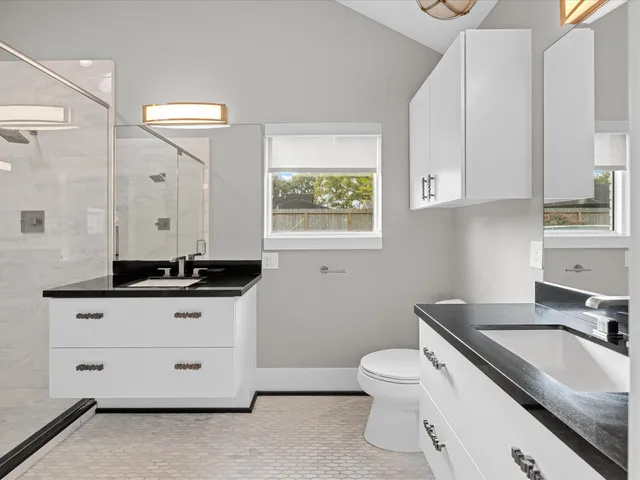 a bathroom with a granite countertop shower sink vanity and mirror