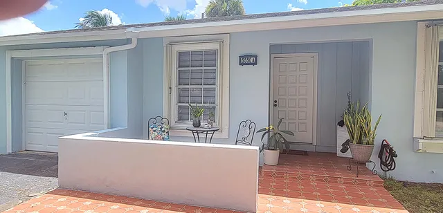 a front view of a house with a yard and palm trees