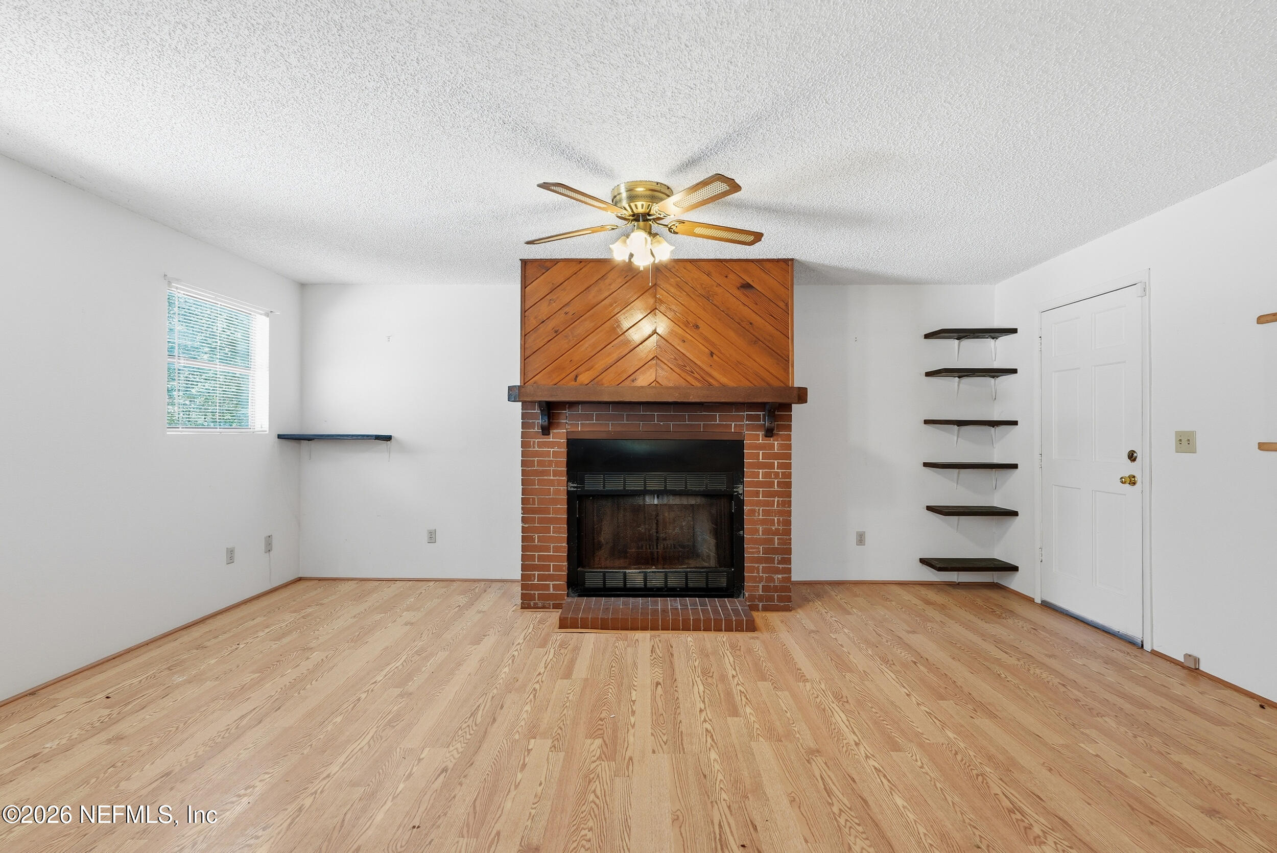 7593 Silver Sands Road Keystone Heights, FL 32656 - Photo 9 of 36 an empty room with a fireplace and fan