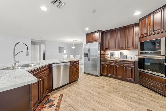 a kitchen with stainless steel appliances granite countertop a refrigerator and a stove top oven