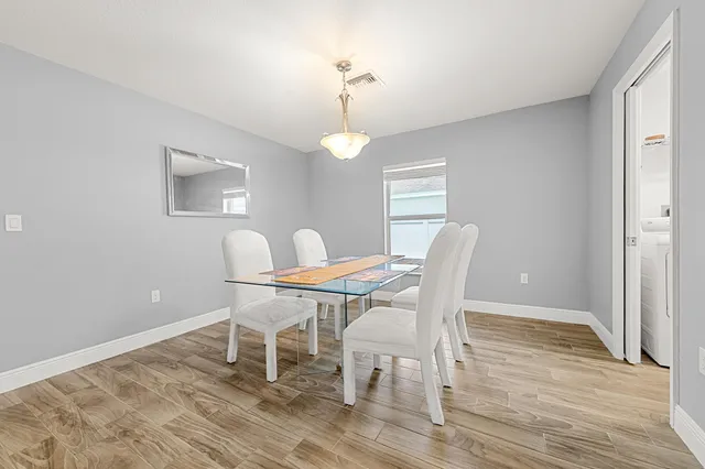 a dining room with wooden floor a chandelier a glass table and chairs