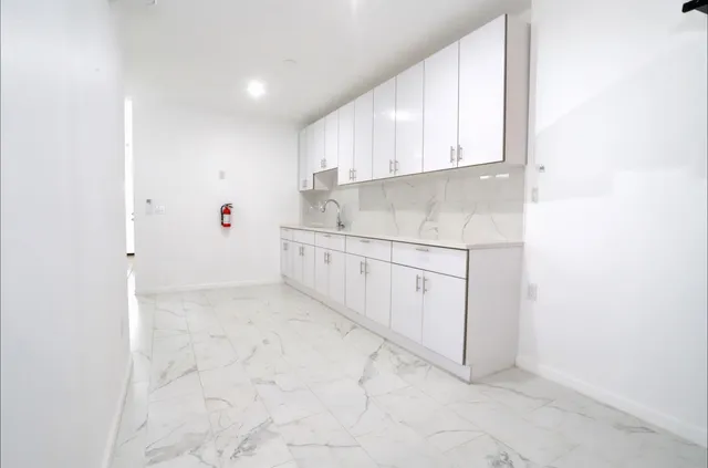 a kitchen with white cabinets and sink