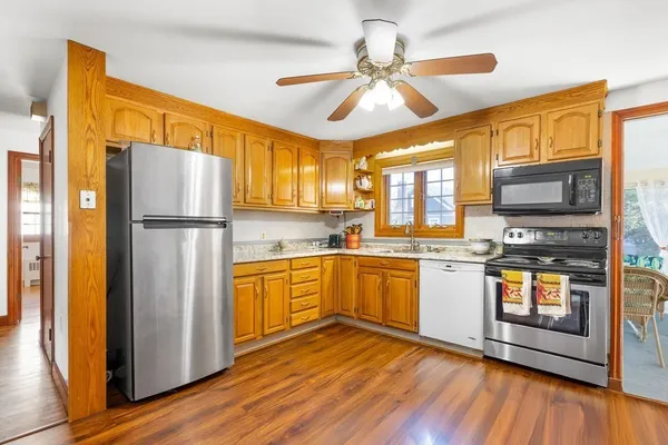 a kitchen with stainless steel appliances granite countertop a refrigerator a stove top oven a sink and dishwasher with wooden floor