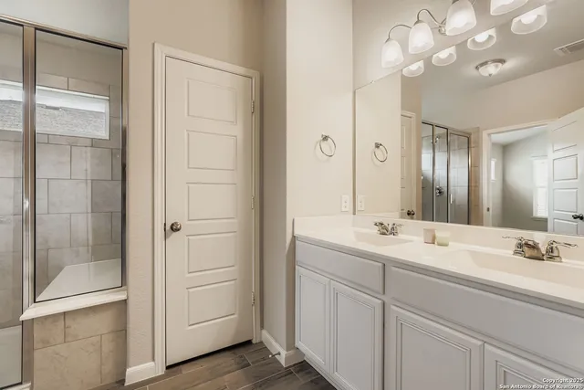 a bathroom with a double vanity sink a large mirror and shower