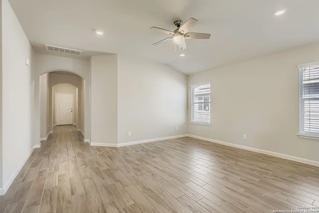 an empty room with wooden floor chandelier and windows