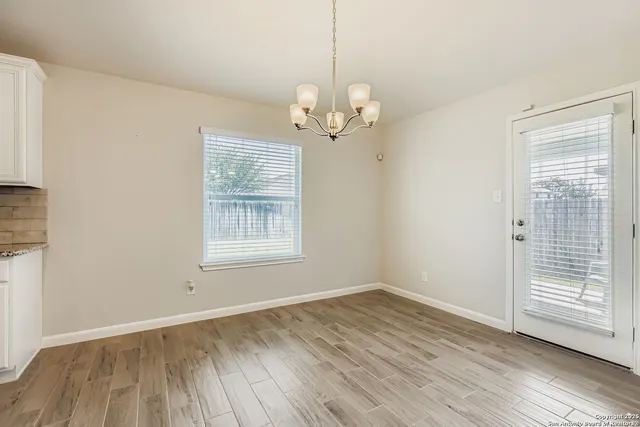 a view of a room with wooden floor chandelier and windows