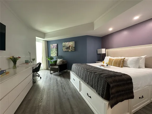 a spacious bedroom with a bed a couch and wooden floor