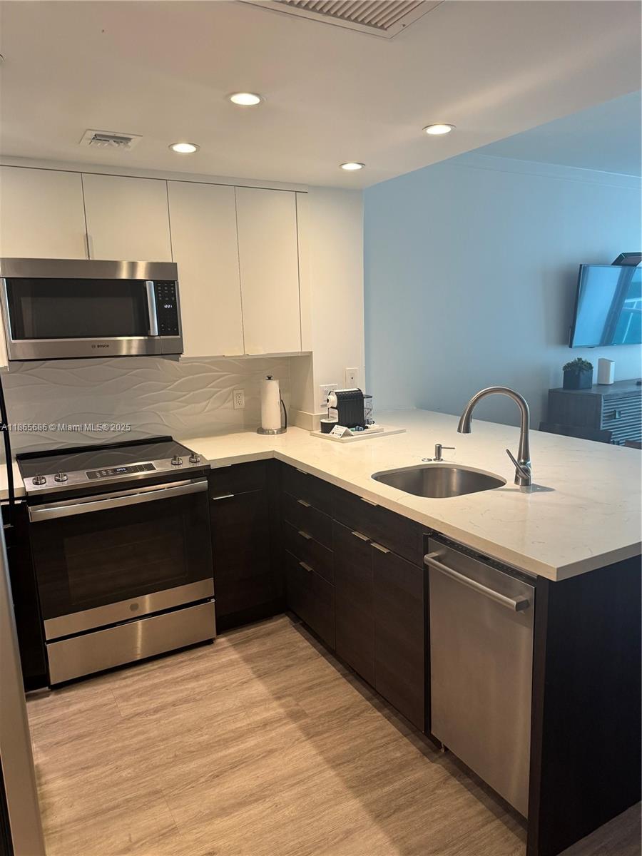 2889 McFarlane Road, Unit 1406 Miami, FL 33133 - Photo 6 of 23 a kitchen with a sink appliances and cabinets