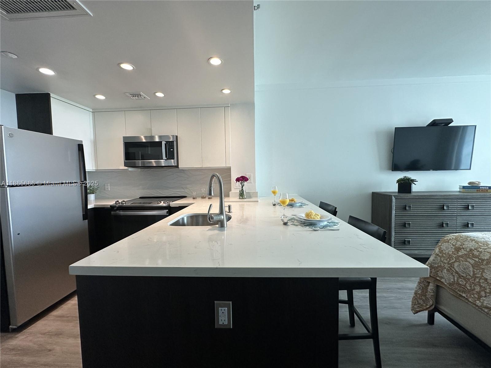 2889 McFarlane Road, Unit 1406 Miami, FL 33133 - Photo 7 of 23 a kitchen with a table chairs refrigerator and microwave