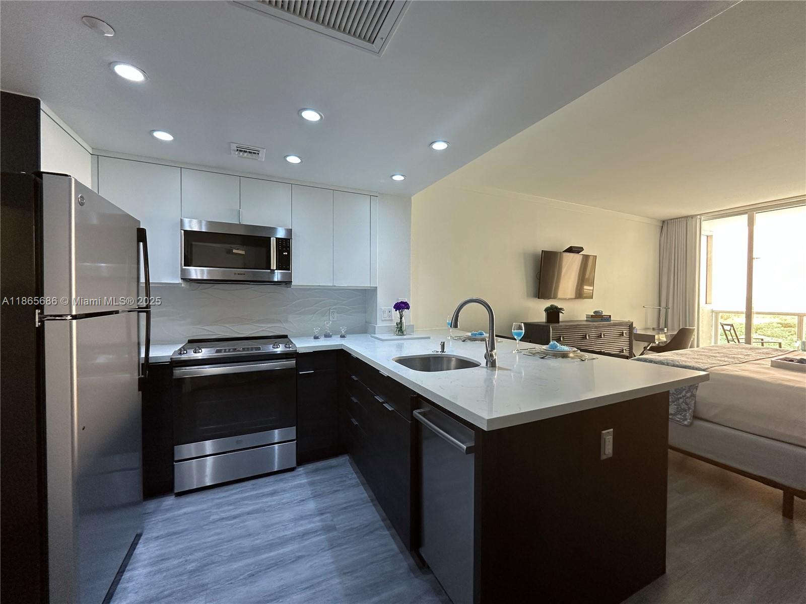 2889 McFarlane Road, Unit 1406 Miami, FL 33133 - Photo 10 of 23 a kitchen with stainless steel appliances granite countertop a sink a stove a refrigerator and cabinets