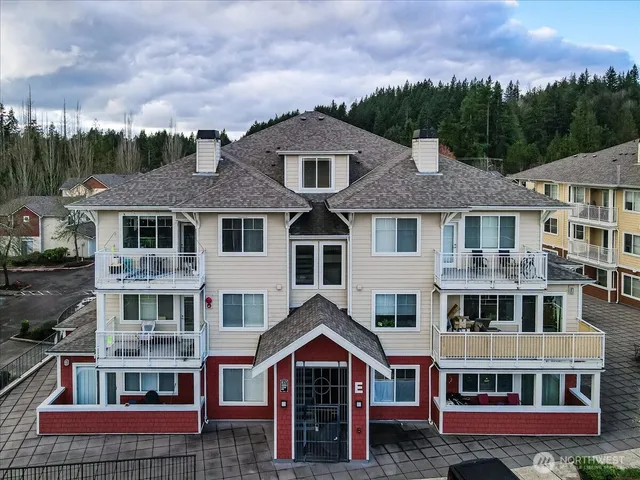 a front view of residential houses with yard and trees in the background